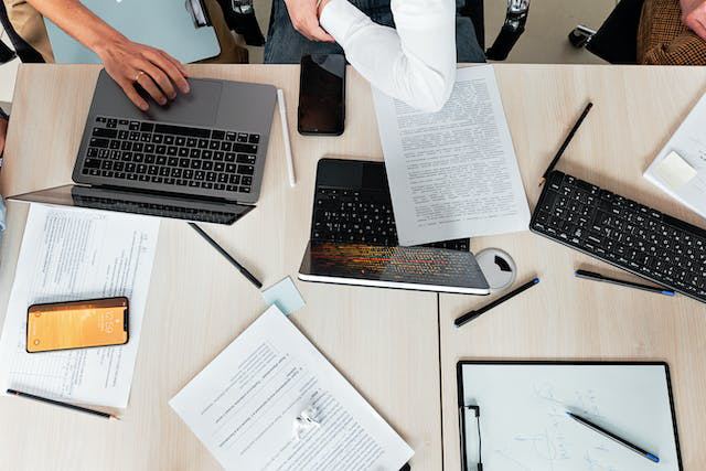A group of people having a meeting with laptops and papers spread on the table